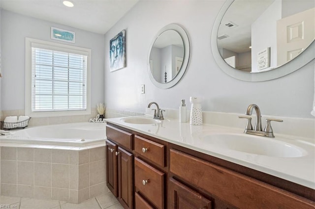 bathroom featuring tile patterned flooring, vanity, and tiled bath