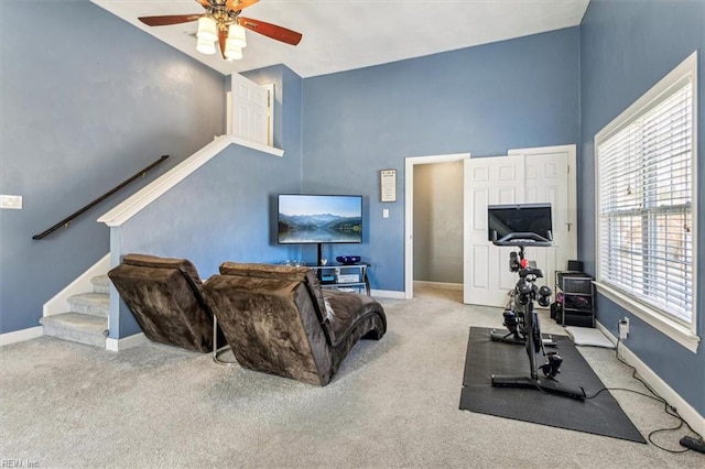 exercise area with a towering ceiling, light colored carpet, and ceiling fan