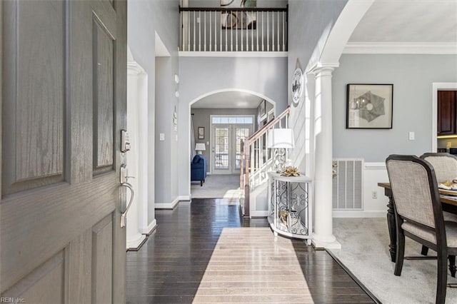 foyer entrance featuring ornamental molding, dark hardwood / wood-style flooring, a high ceiling, and ornate columns