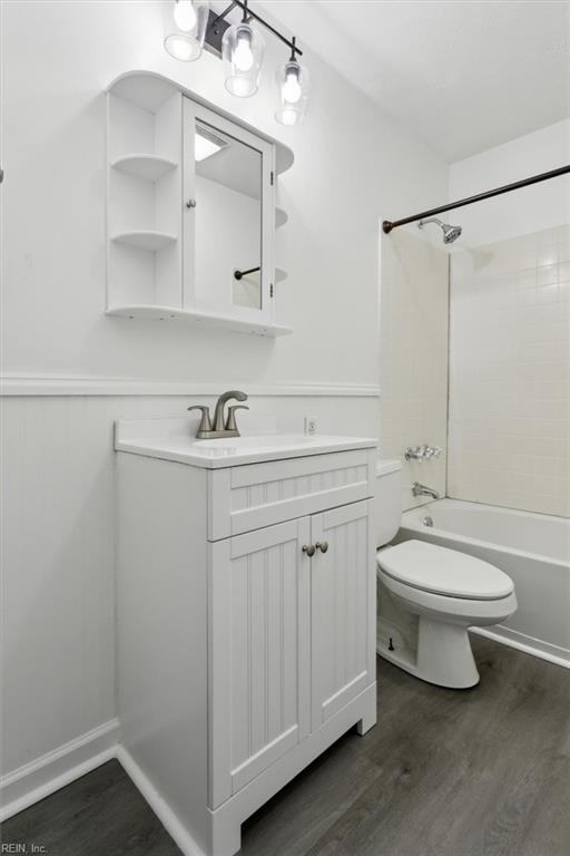 full bathroom with shower / bathtub combination, vanity, toilet, and hardwood / wood-style floors