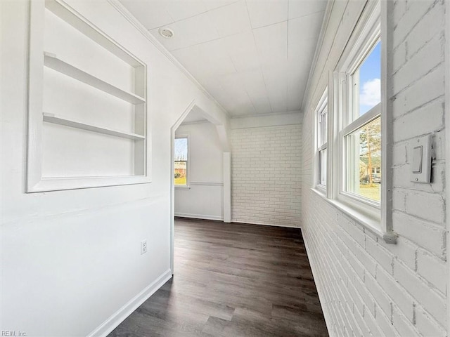 corridor with ornamental molding, brick wall, and dark hardwood / wood-style floors