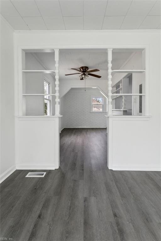 unfurnished living room featuring dark hardwood / wood-style flooring, built in features, ceiling fan, and brick wall