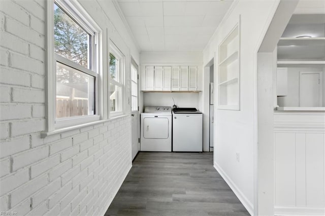 clothes washing area with cabinets, brick wall, separate washer and dryer, and light wood-type flooring