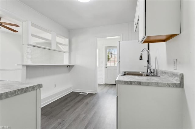 kitchen with sink, dark wood-type flooring, ceiling fan, refrigerator, and white cabinets