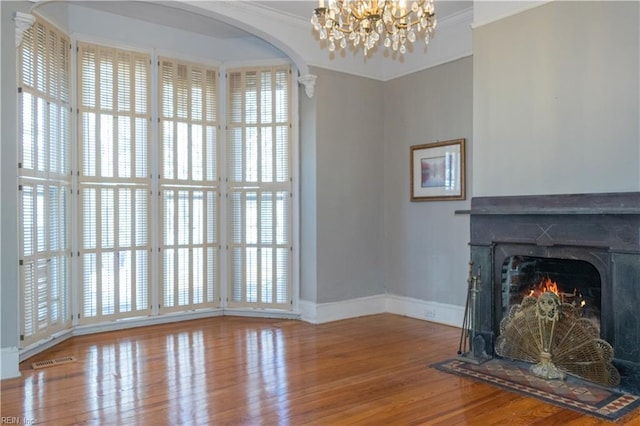 unfurnished living room with ornamental molding, a chandelier, and hardwood / wood-style floors