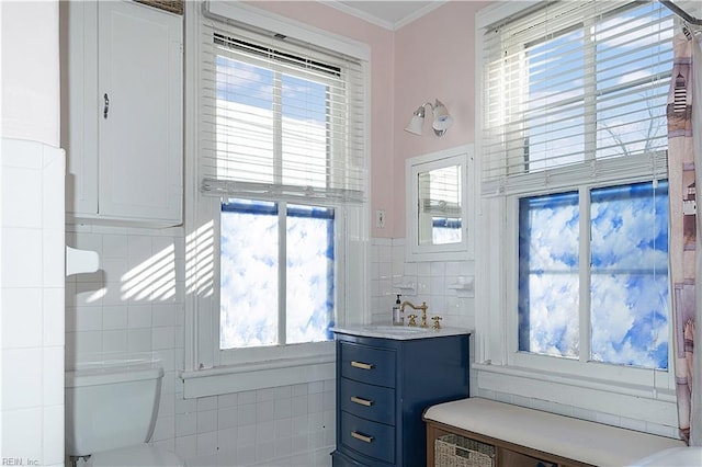 bathroom with tile walls, vanity, ornamental molding, and toilet