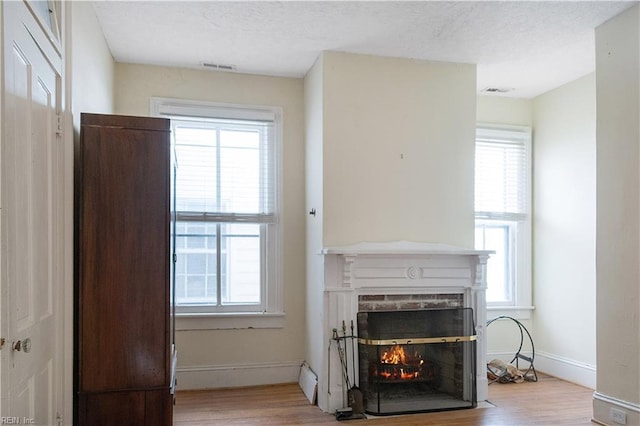 living room with a fireplace, a baseboard radiator, and light wood-type flooring