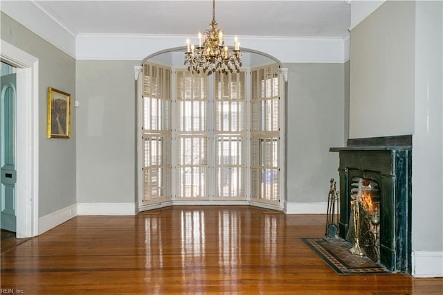 unfurnished living room featuring an inviting chandelier, wood-type flooring, and ornamental molding