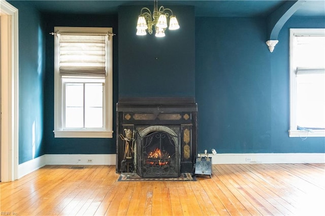 unfurnished living room featuring hardwood / wood-style flooring, a large fireplace, and a chandelier