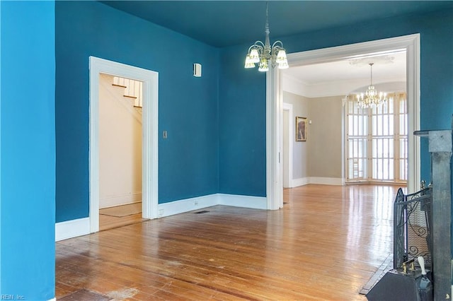 interior space with wood-type flooring, ornamental molding, a premium fireplace, and a chandelier