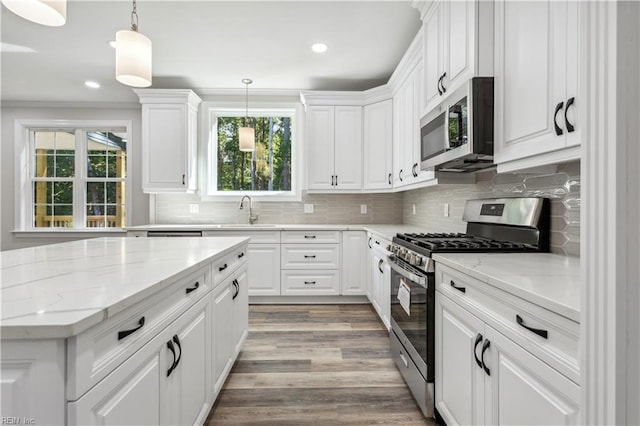 kitchen with appliances with stainless steel finishes, decorative light fixtures, sink, and white cabinets