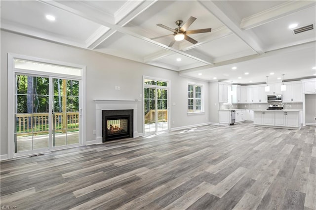 unfurnished living room featuring coffered ceiling, a multi sided fireplace, beam ceiling, and light wood-type flooring