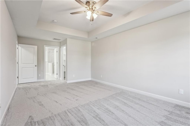 carpeted empty room featuring ceiling fan and a tray ceiling