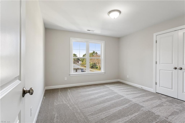 unfurnished bedroom featuring light colored carpet and a closet