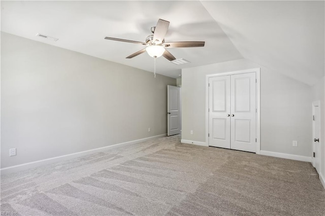 unfurnished bedroom with vaulted ceiling, light colored carpet, ceiling fan, and a closet