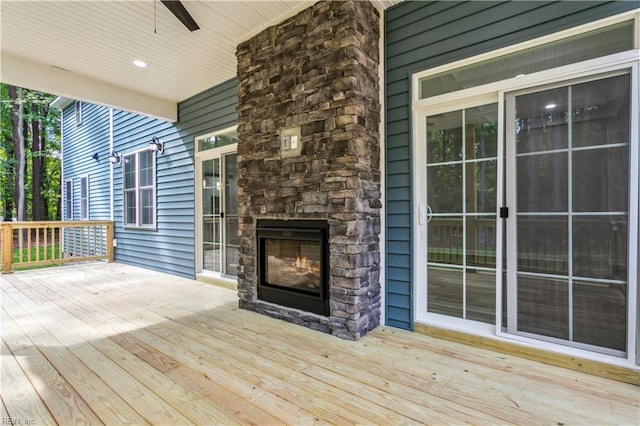 deck with ceiling fan and an outdoor stone fireplace