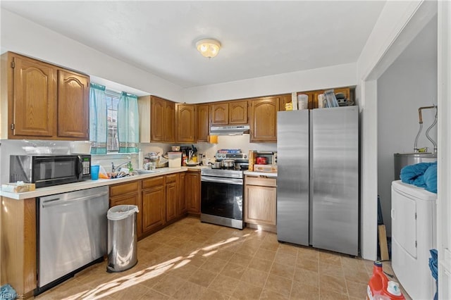 kitchen with appliances with stainless steel finishes, washer / dryer, and sink