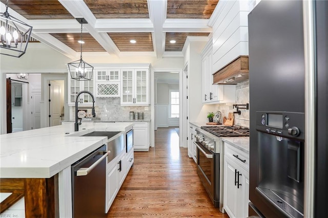 kitchen featuring sink, white cabinetry, light stone counters, stainless steel appliances, and a kitchen island with sink