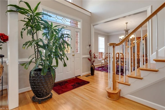 entrance foyer with wood-type flooring, ornamental molding, and a chandelier