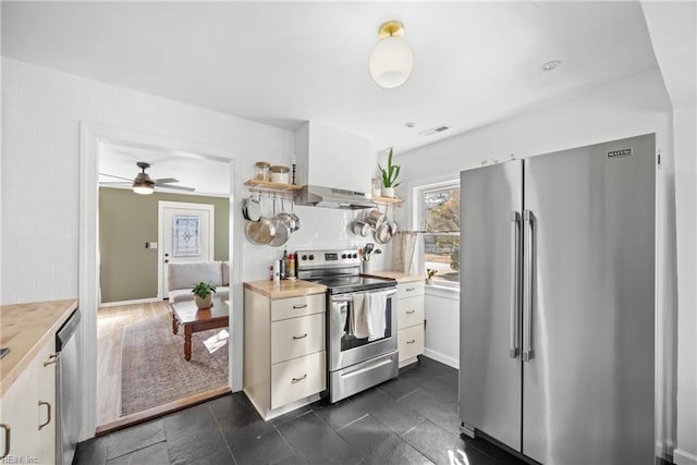 kitchen with white cabinetry, wooden counters, ceiling fan, and appliances with stainless steel finishes