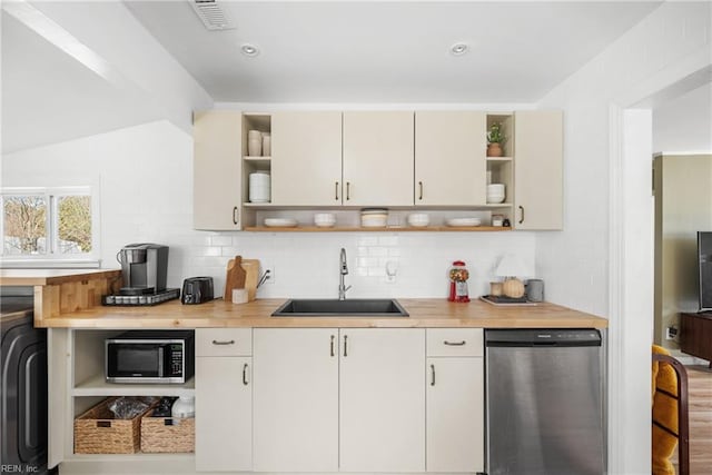 kitchen with butcher block countertops, sink, backsplash, stainless steel appliances, and washer / dryer