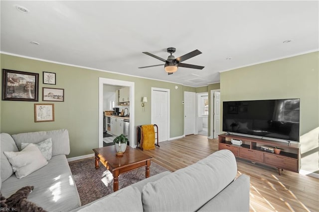 living room featuring crown molding, ceiling fan, and light wood-type flooring