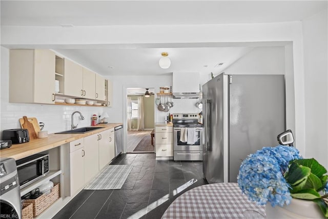 kitchen featuring sink, wooden counters, stainless steel appliances, tasteful backsplash, and washer / clothes dryer