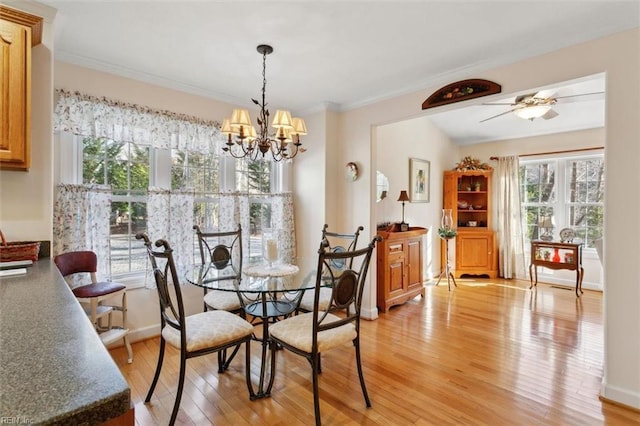 dining room with ornamental molding, a healthy amount of sunlight, ceiling fan with notable chandelier, and light hardwood / wood-style flooring