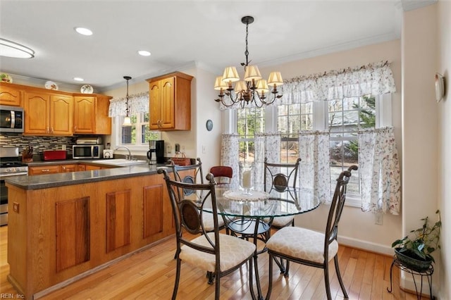 kitchen with ornamental molding, stainless steel appliances, decorative light fixtures, and kitchen peninsula