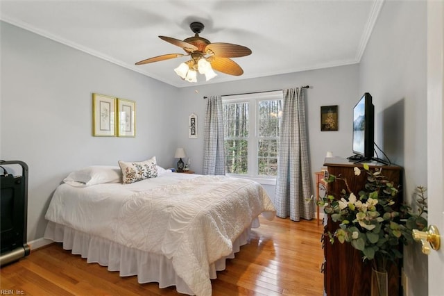 bedroom featuring wood-type flooring, ornamental molding, and ceiling fan