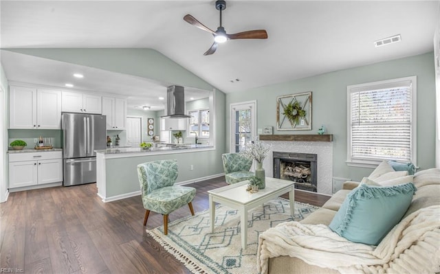 living room featuring ceiling fan, lofted ceiling, a fireplace, and dark hardwood / wood-style flooring