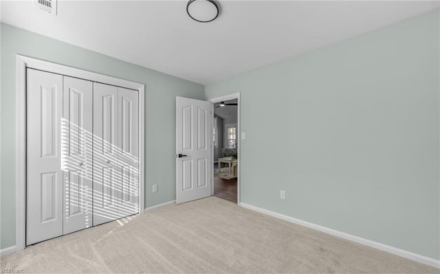 unfurnished bedroom featuring light carpet and a closet