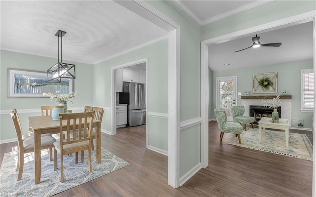 dining space with a healthy amount of sunlight, dark hardwood / wood-style floors, ceiling fan with notable chandelier, and ornamental molding