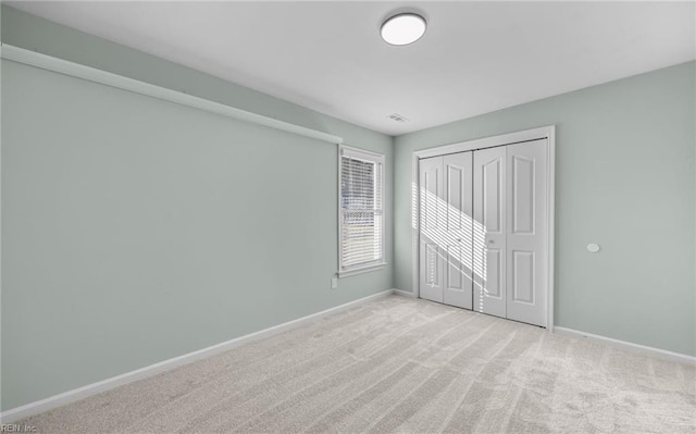 unfurnished bedroom with light colored carpet and a closet