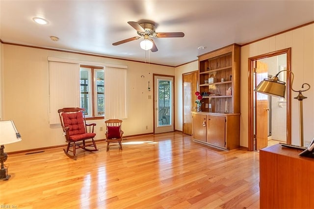 living area with crown molding, ceiling fan, and light wood-type flooring