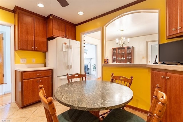 kitchen featuring crown molding, light tile patterned floors, white fridge, pendant lighting, and ceiling fan with notable chandelier