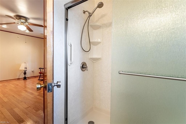 bathroom featuring a shower with door, hardwood / wood-style floors, and ceiling fan