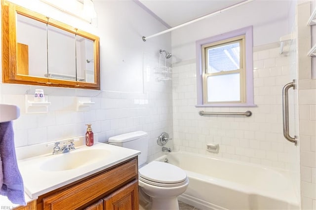 full bathroom with tile walls, vanity, tiled shower / bath, and toilet