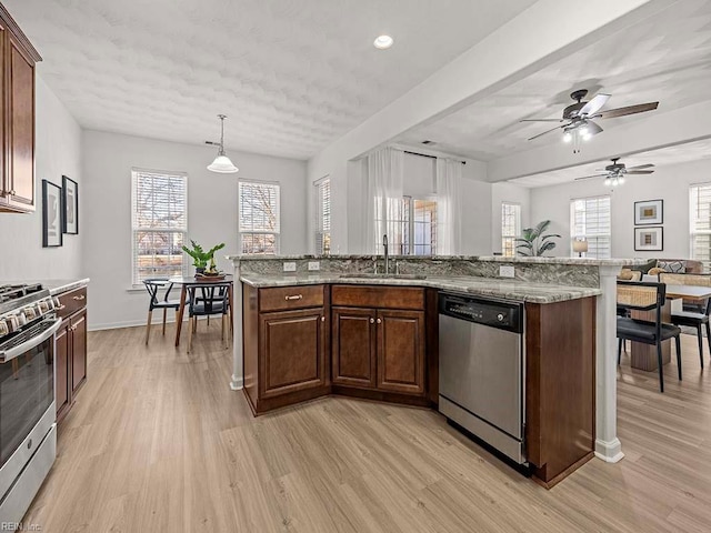 kitchen featuring sink, stainless steel appliances, hanging light fixtures, and light wood-type flooring