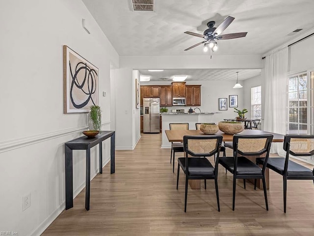 dining room with ceiling fan and light wood-type flooring