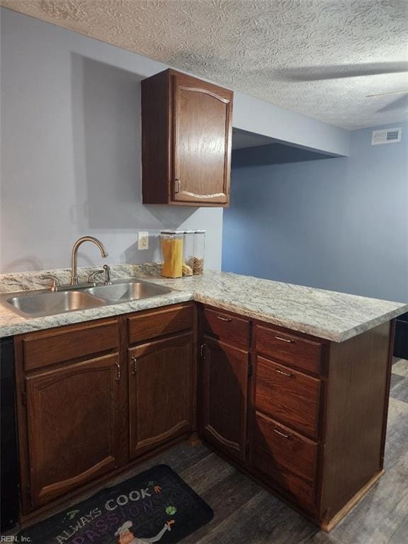 kitchen featuring sink, a textured ceiling, dark hardwood / wood-style floors, and kitchen peninsula