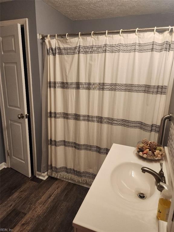 bathroom with vanity, curtained shower, hardwood / wood-style floors, and a textured ceiling