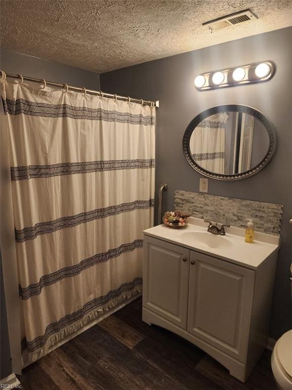 bathroom with vanity, tasteful backsplash, wood-type flooring, a textured ceiling, and toilet