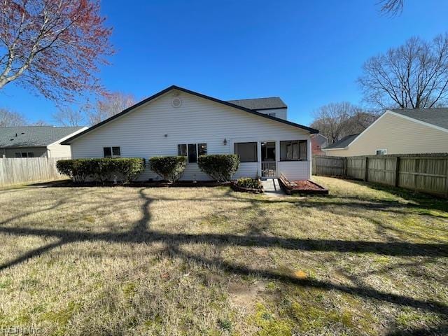 rear view of house with a yard, a fenced backyard, and a sunroom