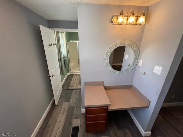 full bathroom featuring wood finished floors, a shower with shower door, baseboards, a textured ceiling, and a notable chandelier
