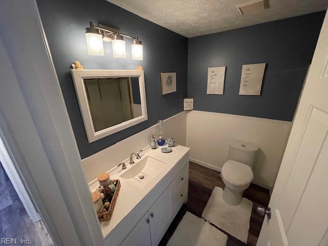 bathroom featuring visible vents, a textured ceiling, vanity, and toilet
