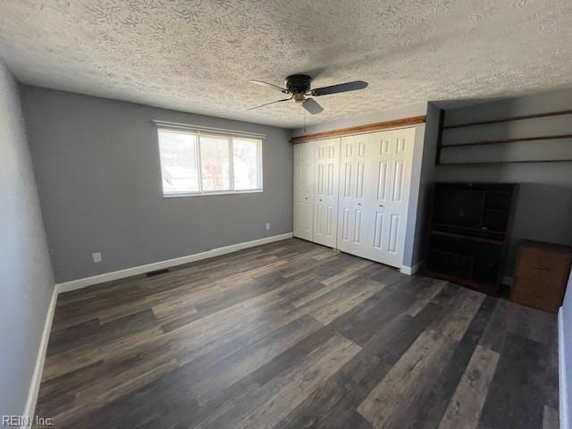 unfurnished bedroom with dark wood-style floors, baseboards, and a textured ceiling