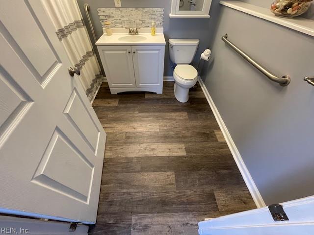 bathroom with vanity, toilet, wood finished floors, and baseboards