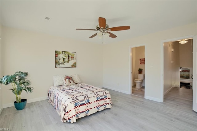 bedroom featuring ceiling fan, a fireplace, connected bathroom, and light hardwood / wood-style floors