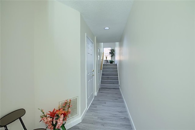 hallway with a textured ceiling and light wood-type flooring